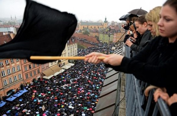 A girl waves a black flag as people take part in a nationwide strike and demonstration to protest against a legislative proposal for a total ban of abortion on October 3, 2016 in Warsaw. Thousands of women dressed in black protested across Poland in the "Women strike" campaign against a proposed near-total abortion ban in the devoutly Catholic country where legislation is already among the most restrictive in Europe. / AFP PHOTO / JANEK SKARZYNSKI